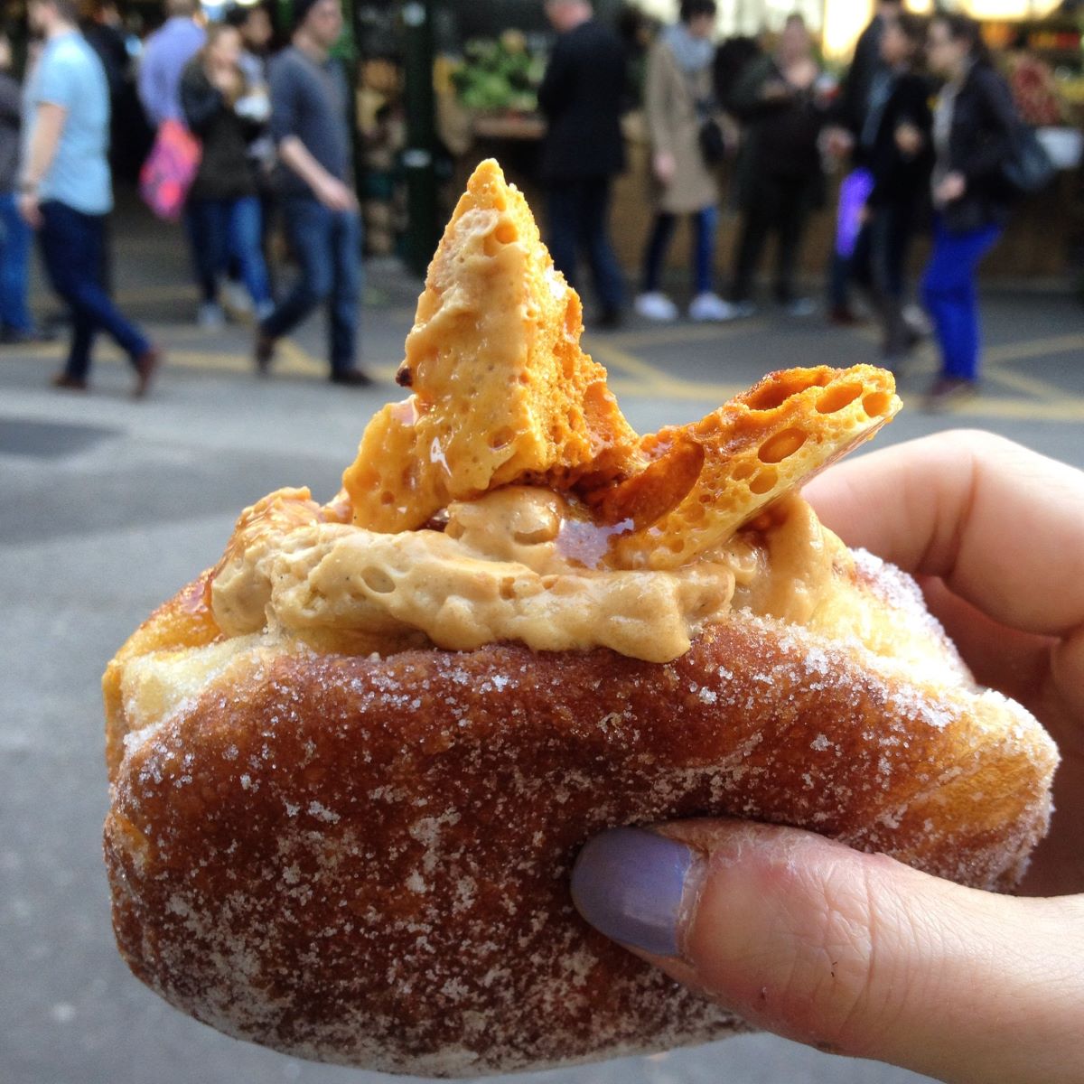 A person holding a salted honeycomb doughnut at Bread Ahead in London. 