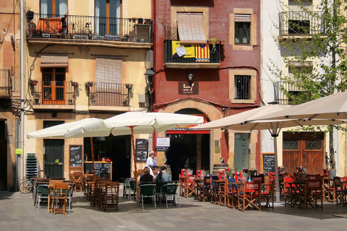 People sitting outside at a terrace eating in Plaça del Rei. 