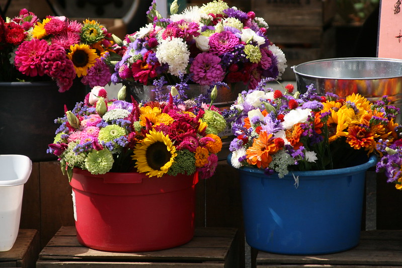 Two buckets brimming with vibrant bouquets of fresh flowers sitting on top of a table.