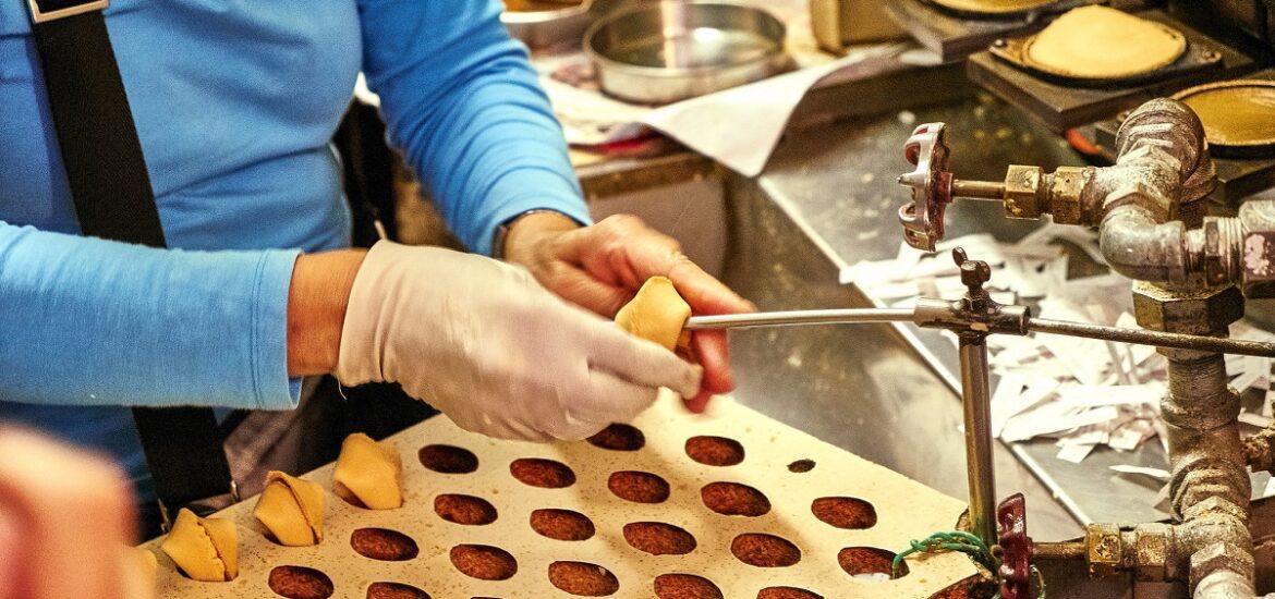 Woman folding fortune cookies at the San Francisco Golden Gate Fortune cookie factory