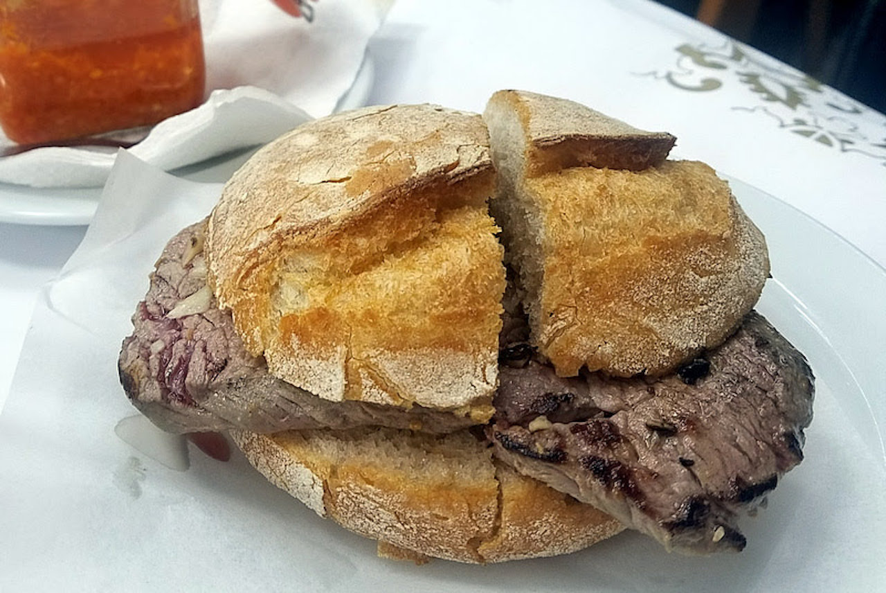 Prego, or Portuguese steak sandwich, on a plate with hard roll