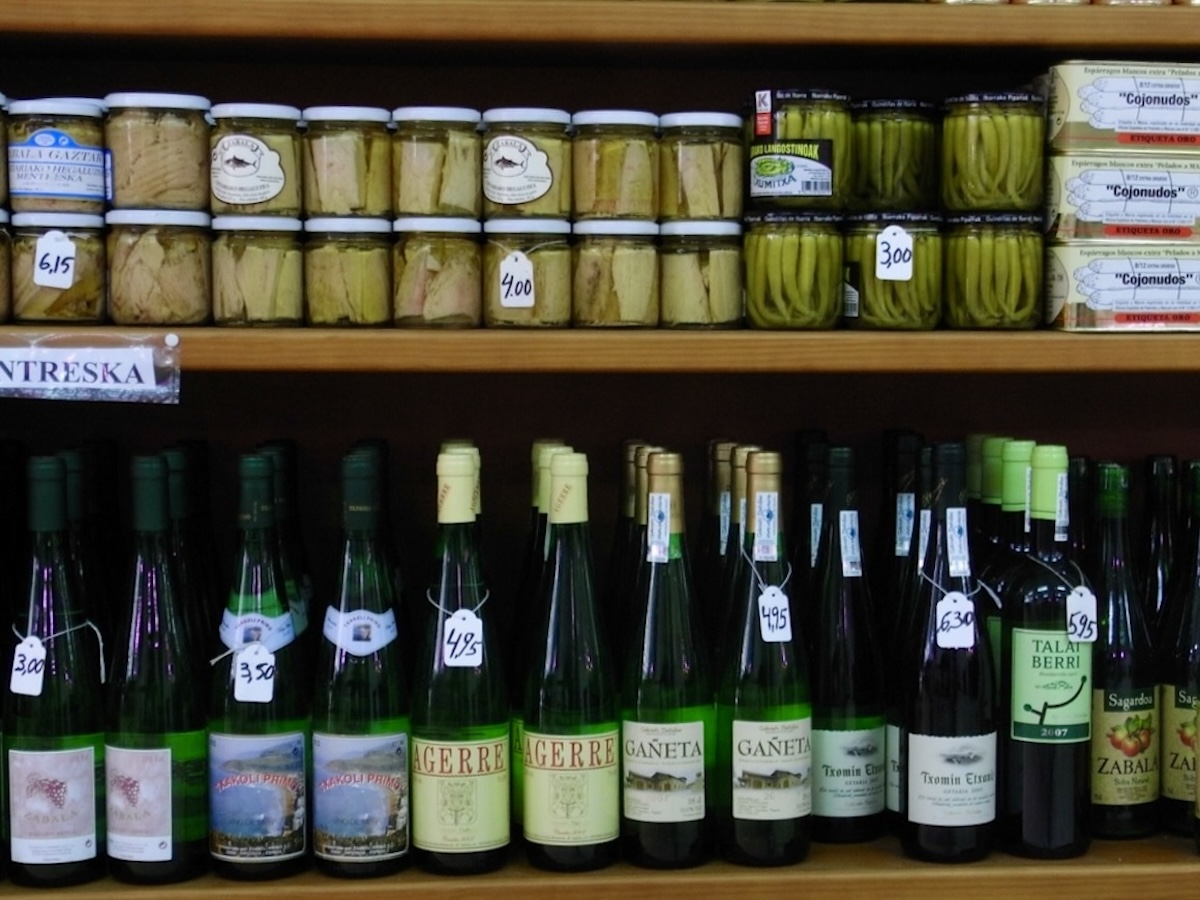 bottles of wine and cans of preserved food on shelves in a shop