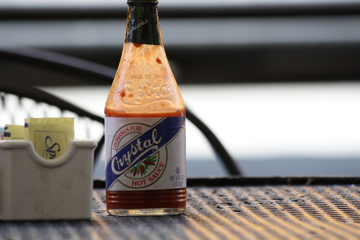 Bottle of Crystal Hot Sauce sits on an empty restaurant table next to a pack of sugar