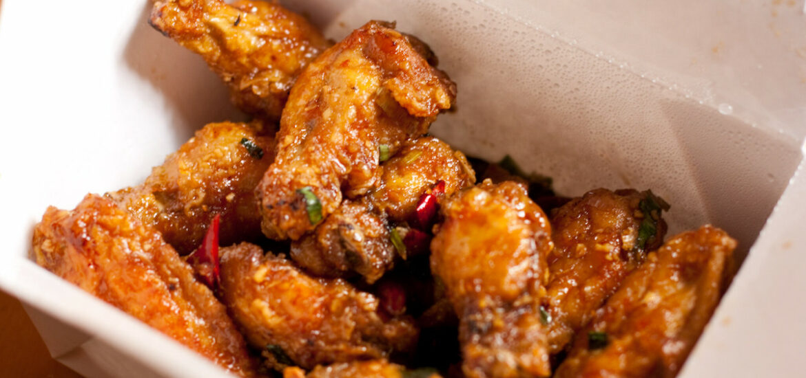 Close up of a white to go box filled with crispy chicken wings