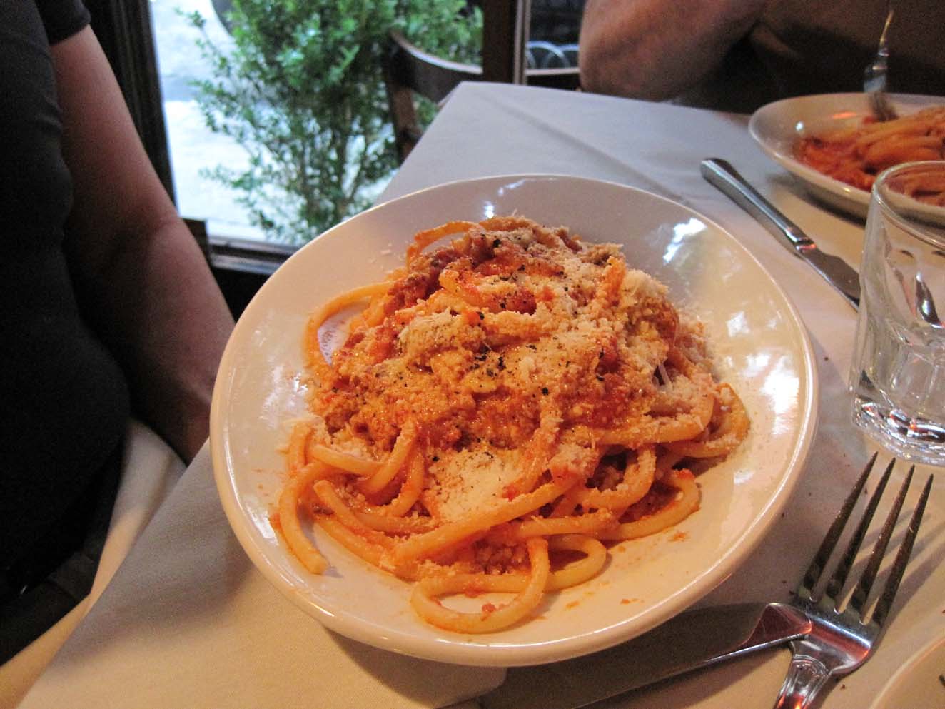 Plate of spaghetti with red pasta sauce and grated parmesean cheese at a restaurant