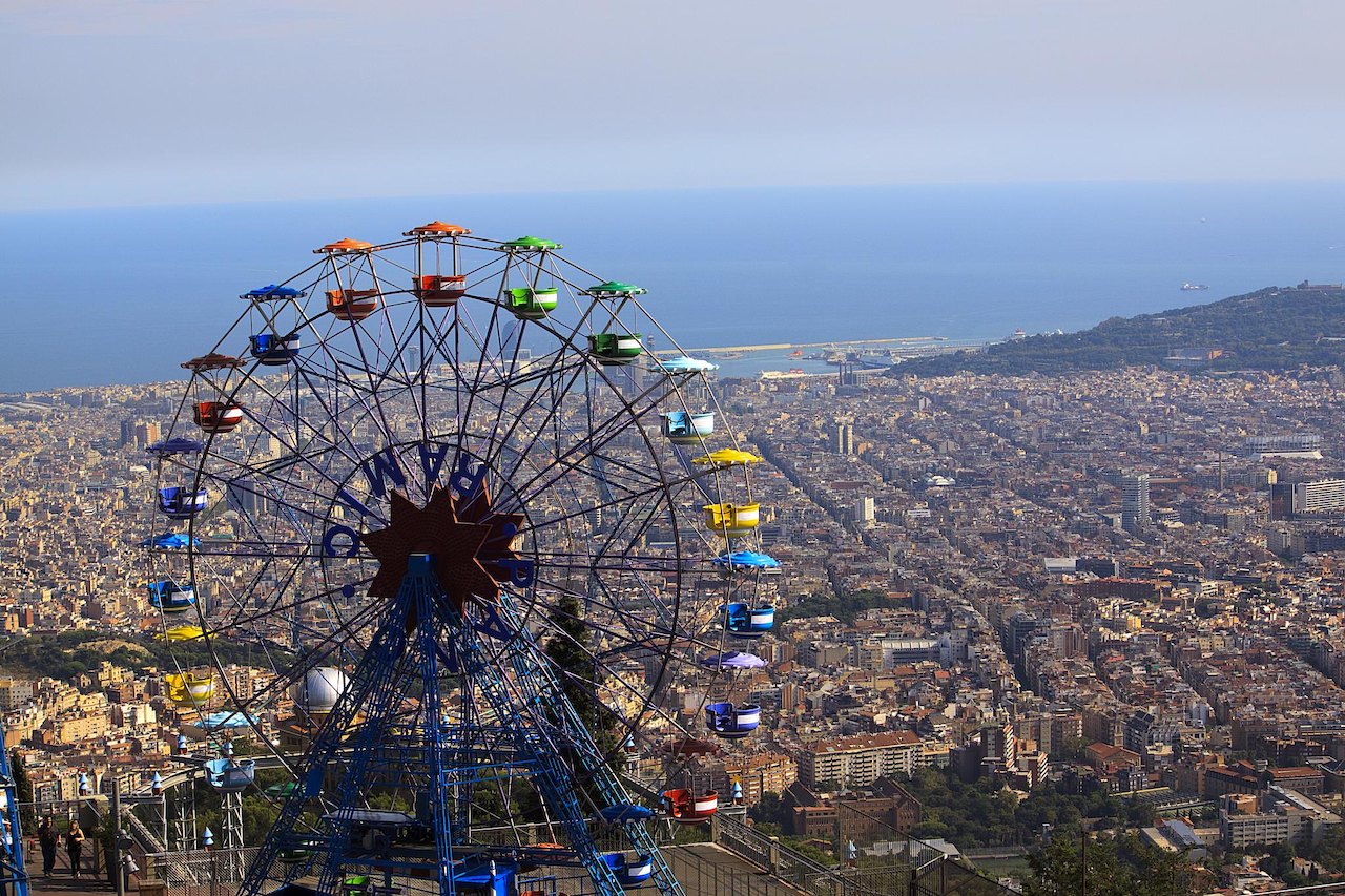 Tibidabo ferris wheel overlooking Barcelona and the city's beach during the day