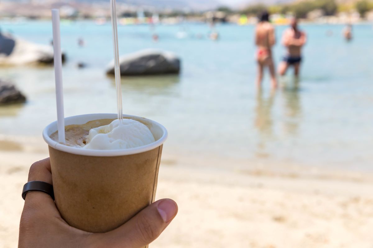 Cold Frappe Coffee with an ice cream scoop, on the beach, in a to go cup