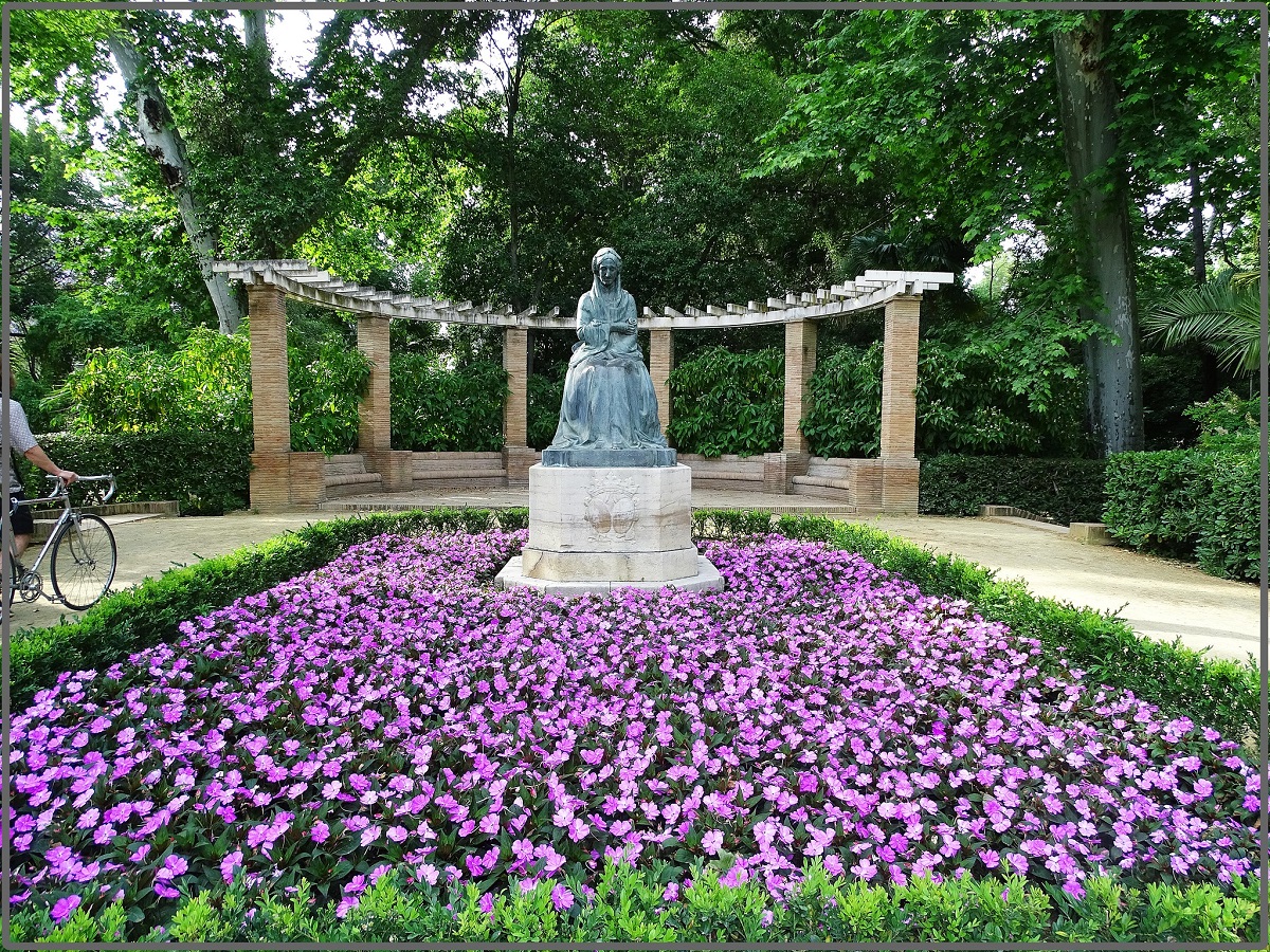Statue surrounded by flowers at a park in Seville