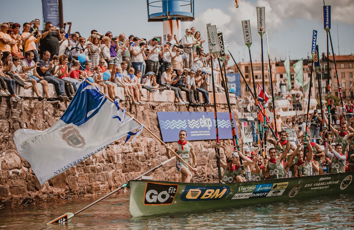 A crowd cheering at the Bandera de la Concha Regatta as a rowing team competes. 