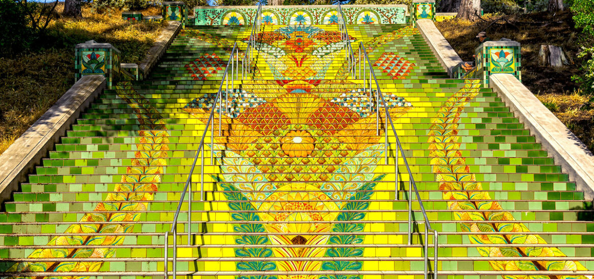 A highly decorated staircase outside in a park. Tiles are painted yellow, green, and red