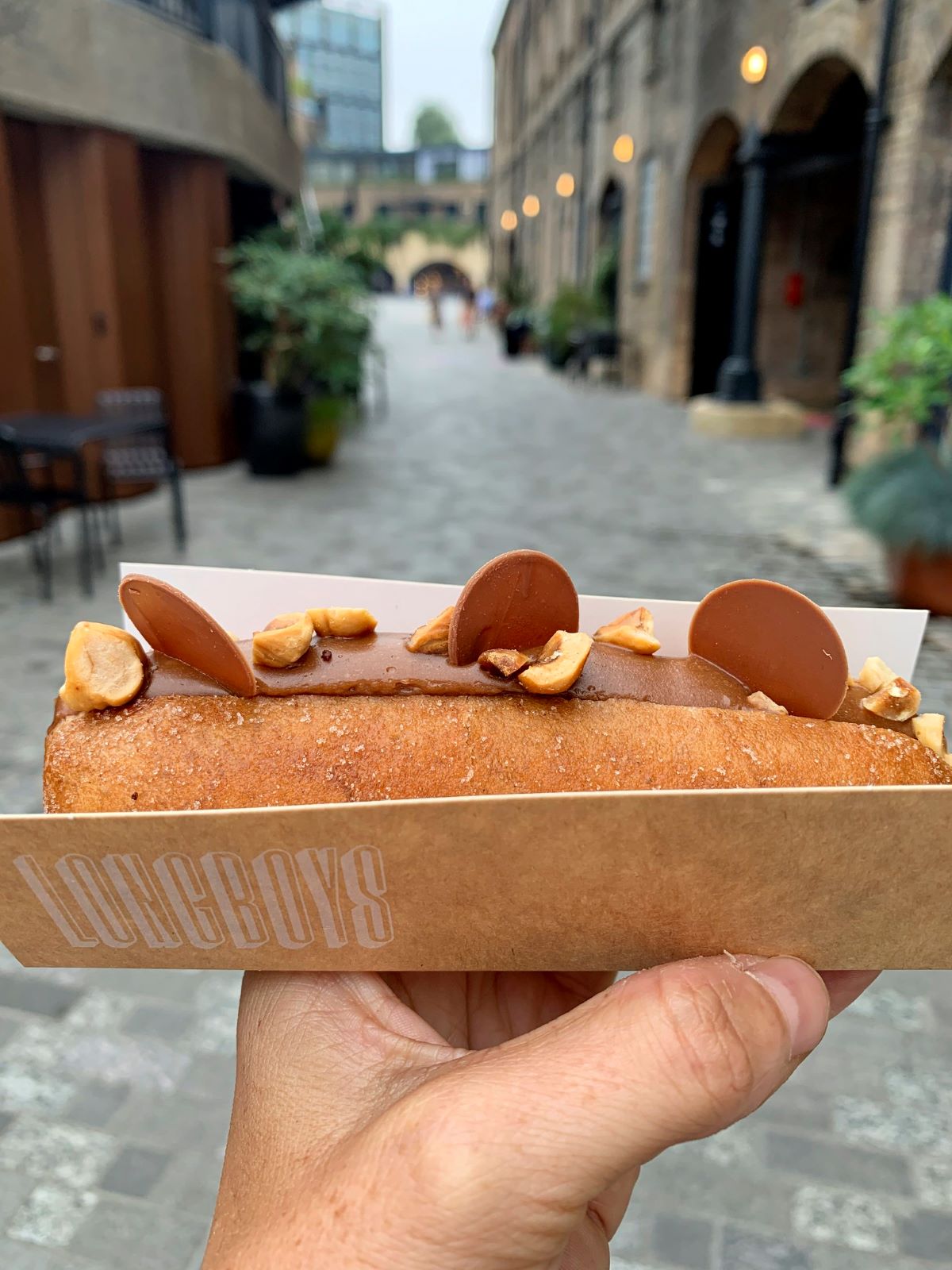 A person holding up a chocolate doughnut from Longboys in London. 