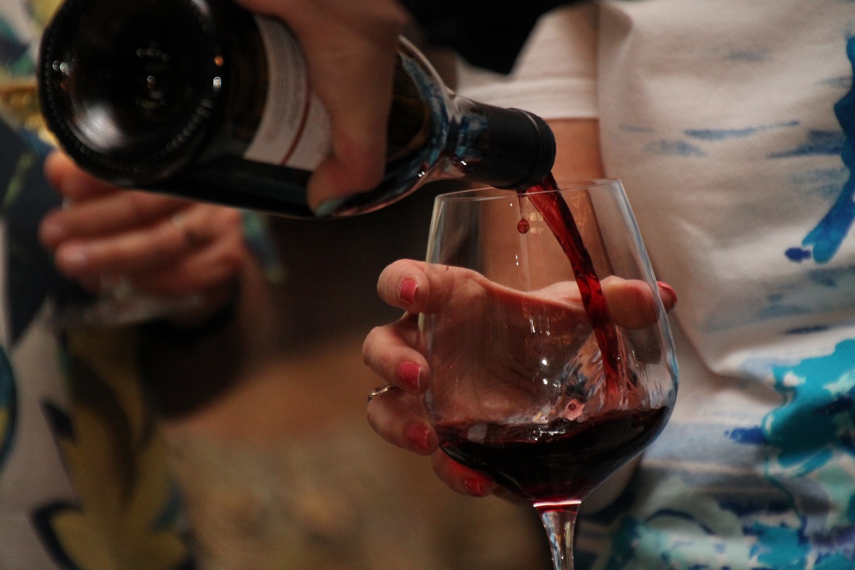 Person pouring a glass of Pinot Noir red wine into a wine glass
