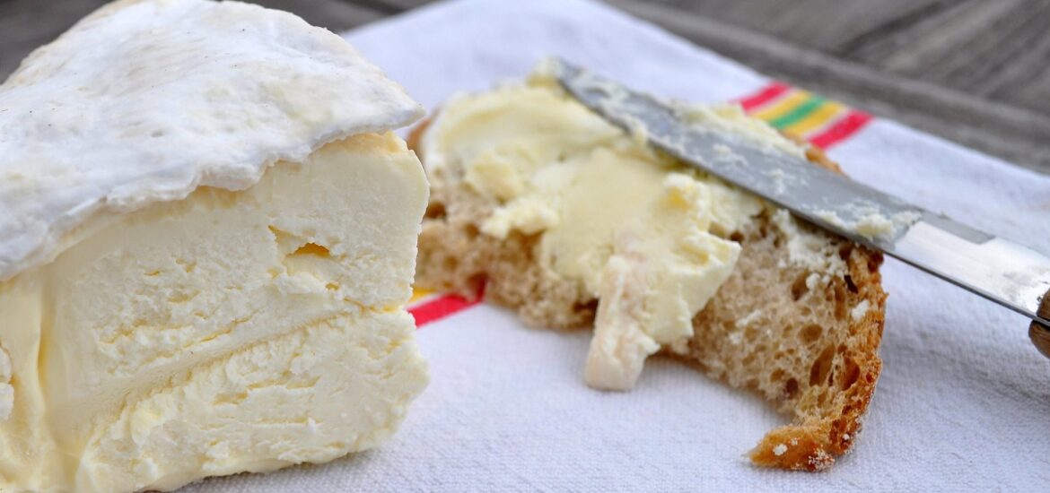 Wedge of cheese smeared on bread with knife