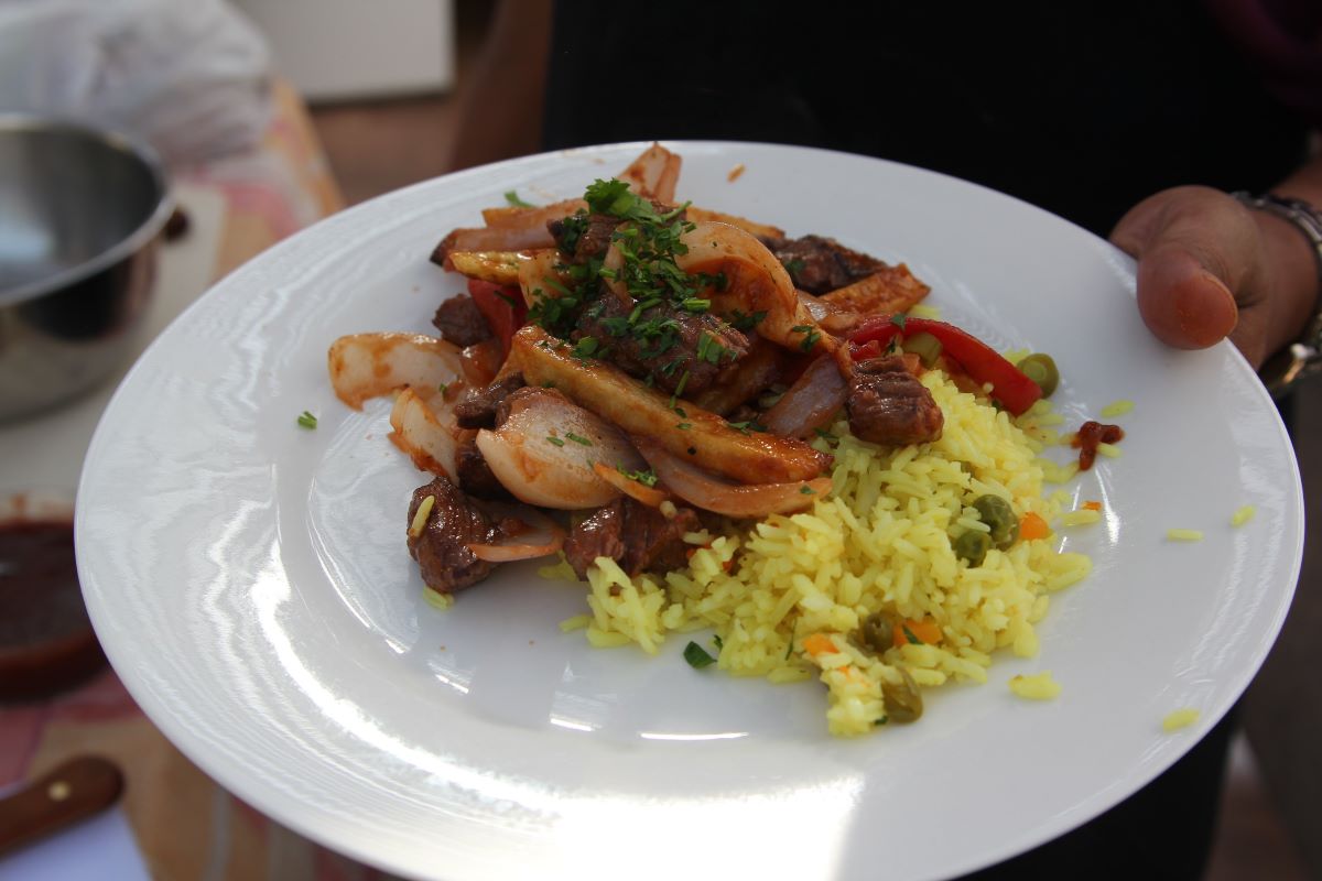 A chef holding a plate of lomo saltado in NYC. 