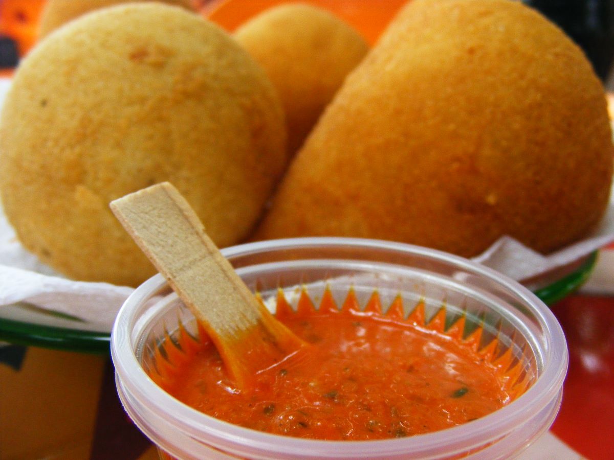 coixinhas sitting on a plate with hot sauce in front of them. 