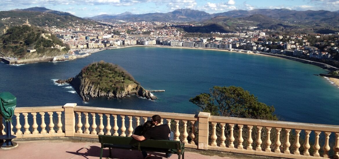 People sitting at an overlook in San Sebastian.