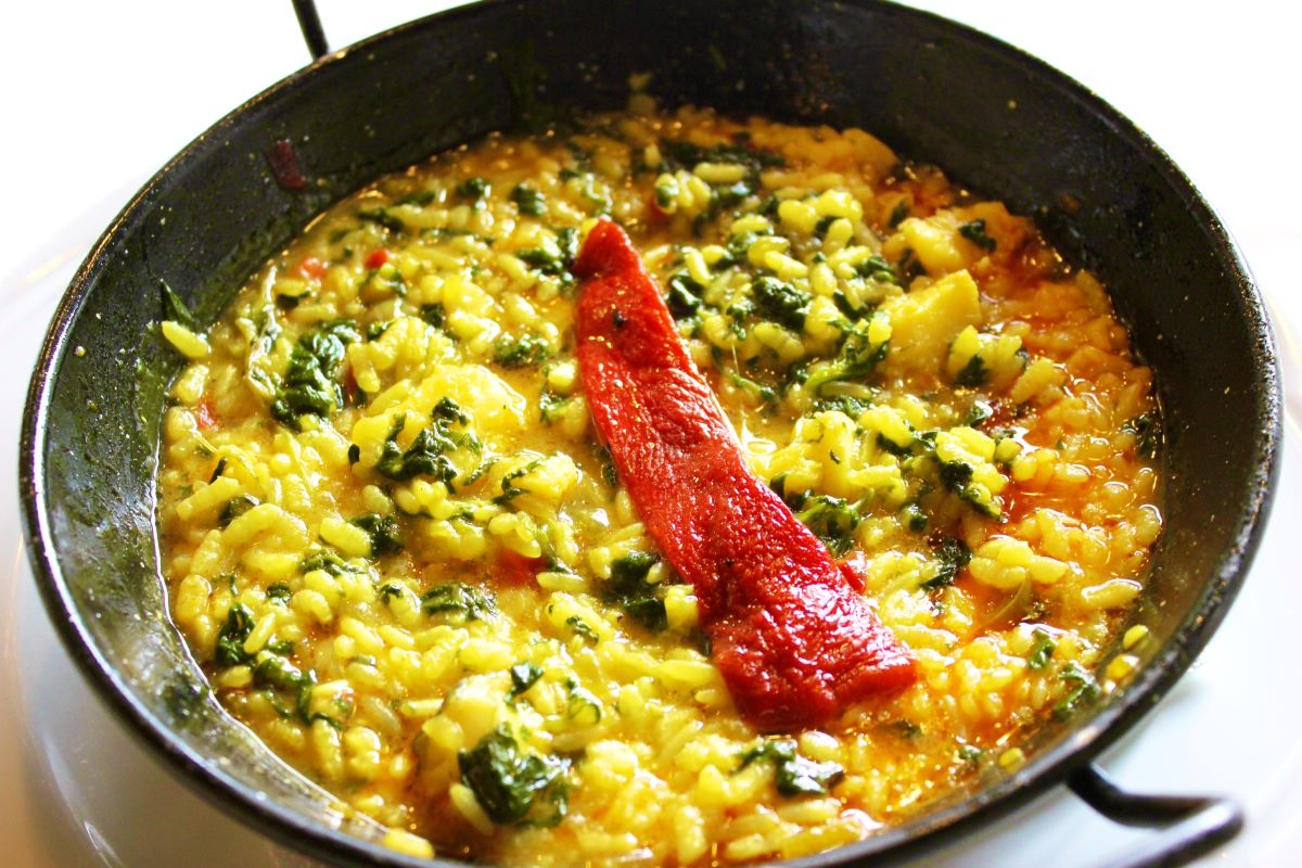 Paella in a sauce pan with a Spanish piquillo peppers.