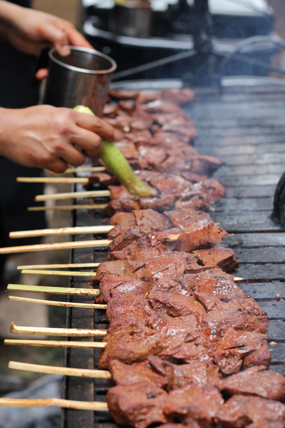 A chef grilling rows of Anticuchos at NYC Peruvian restaurants