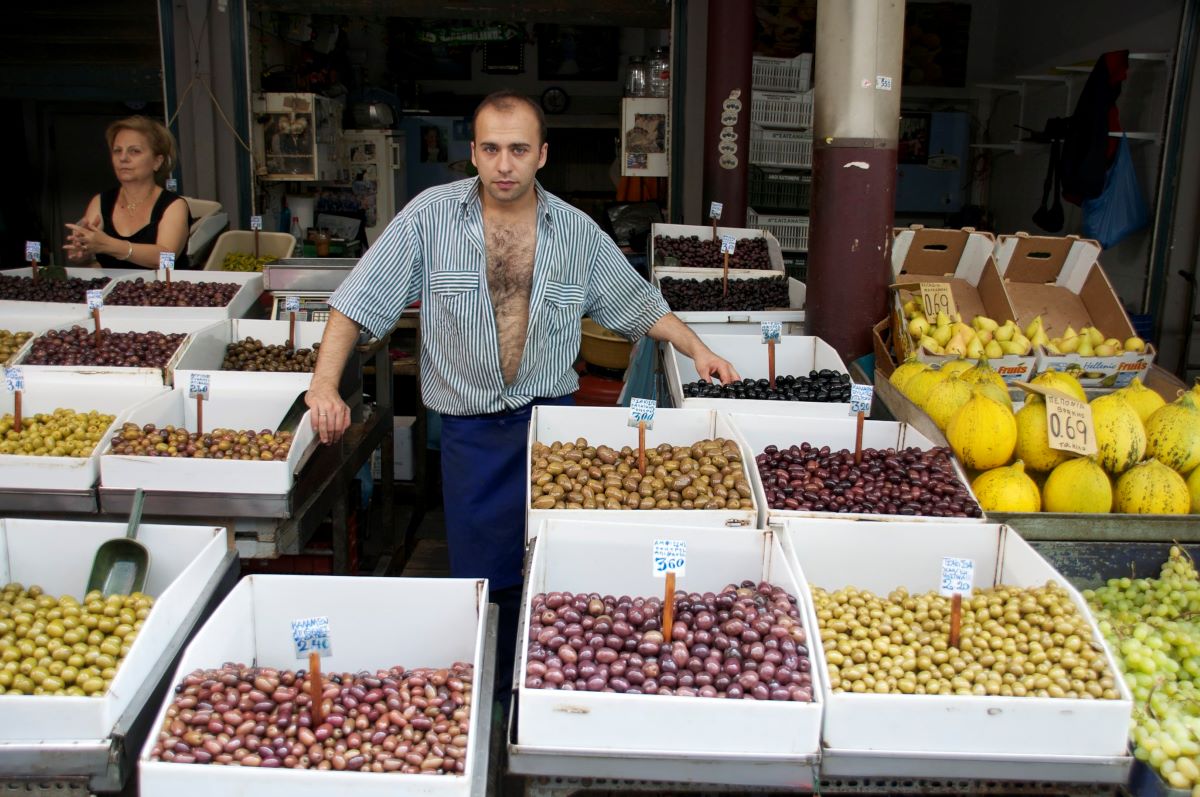 Man standing near displays of olives of different colors