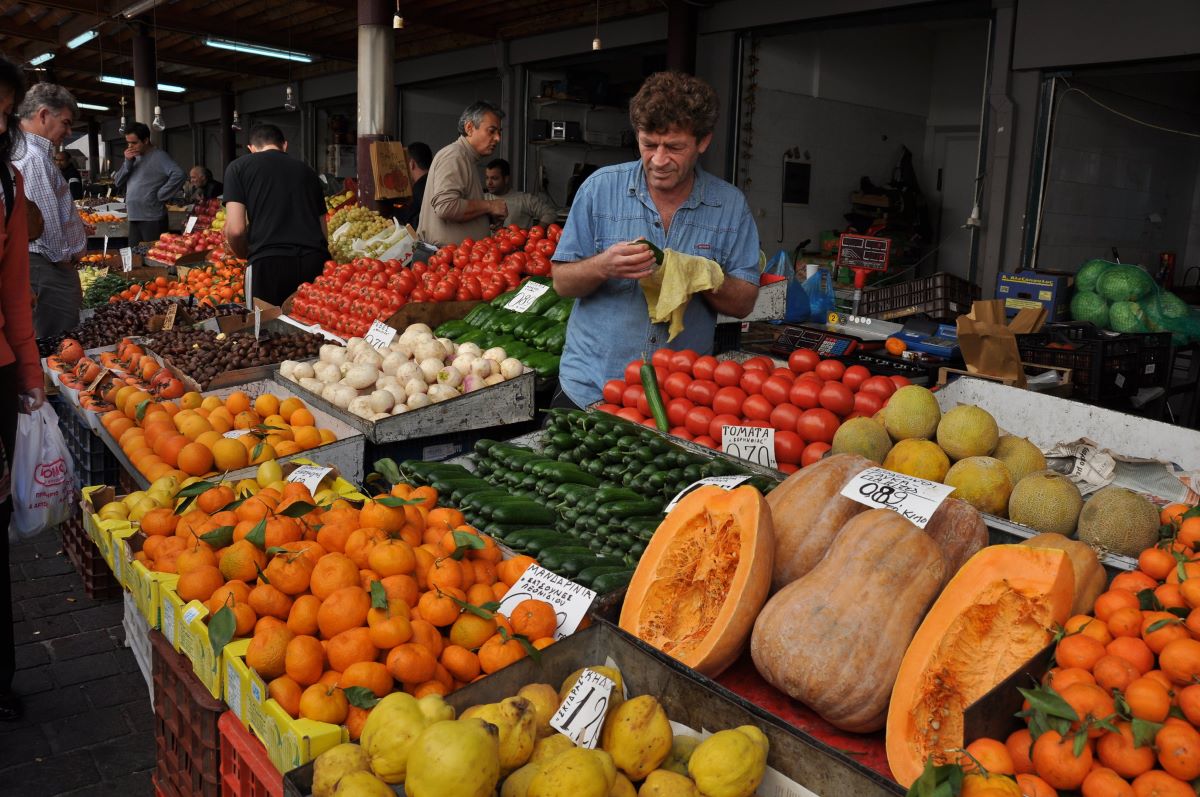 man standing beside a display of fruit in a market