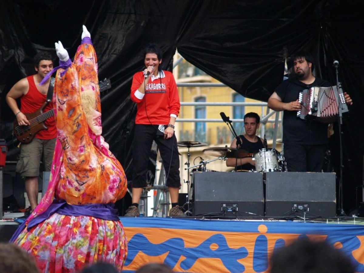 A stage with a band performing and a large puppet dancing at Semana Grande in Spain. 