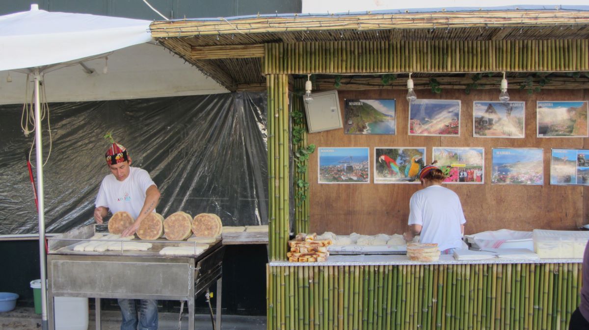 two people working in a food stall selling round breads. 