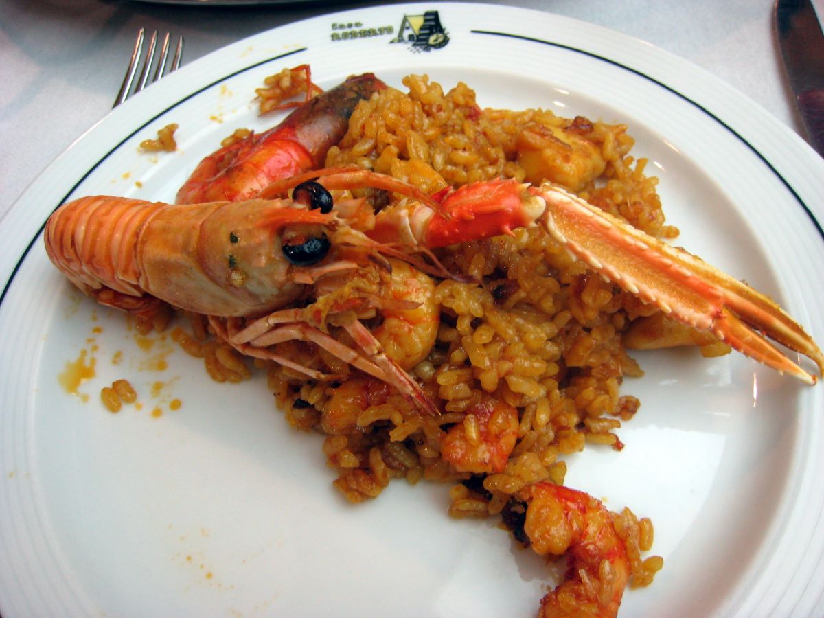 white plate topped with paella and a large shrimp