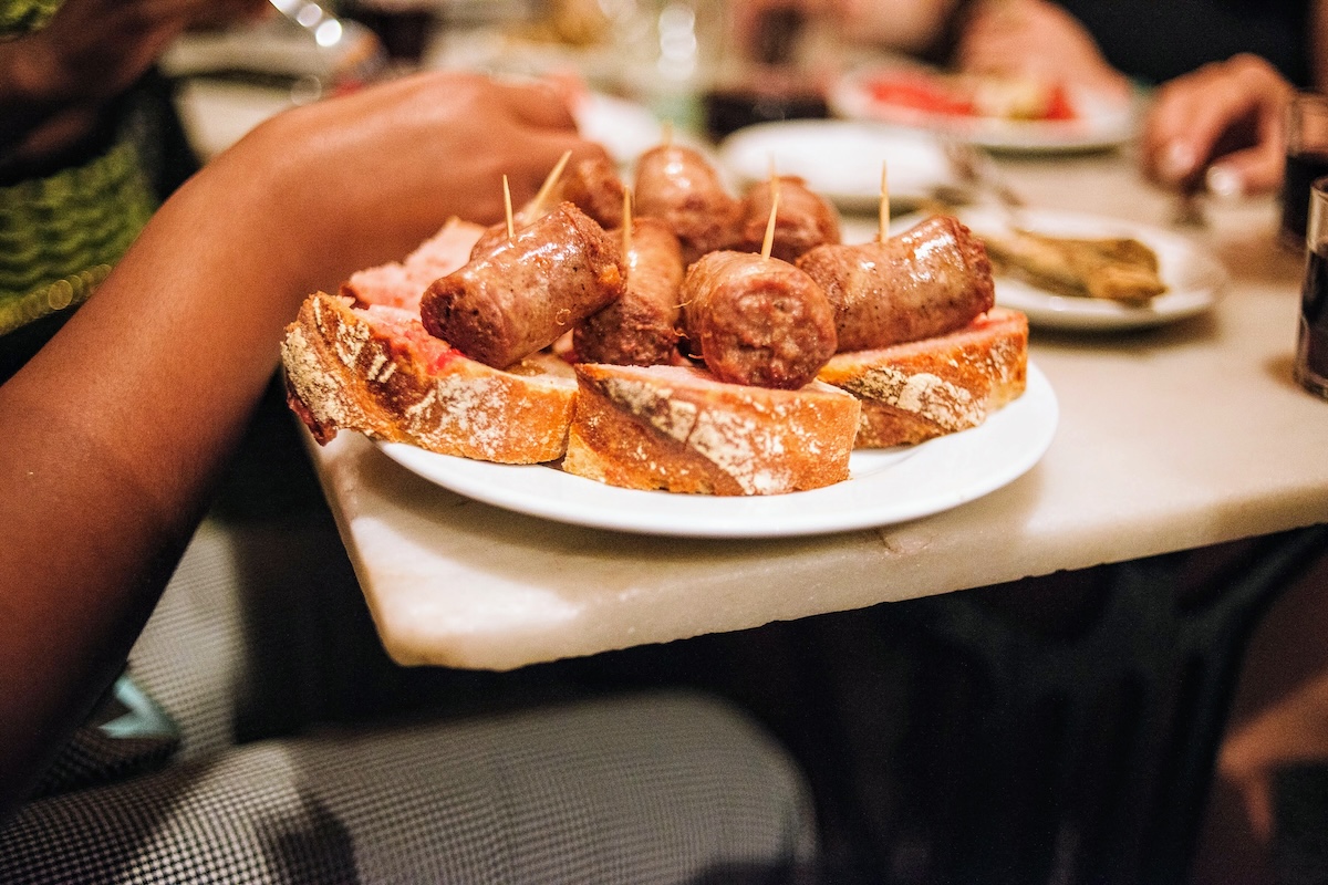 person eating tapas from a large white plate.