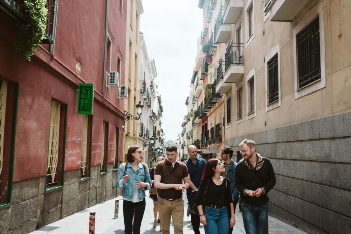 a group of people walking down a narrow street in Madrid, Spain. 