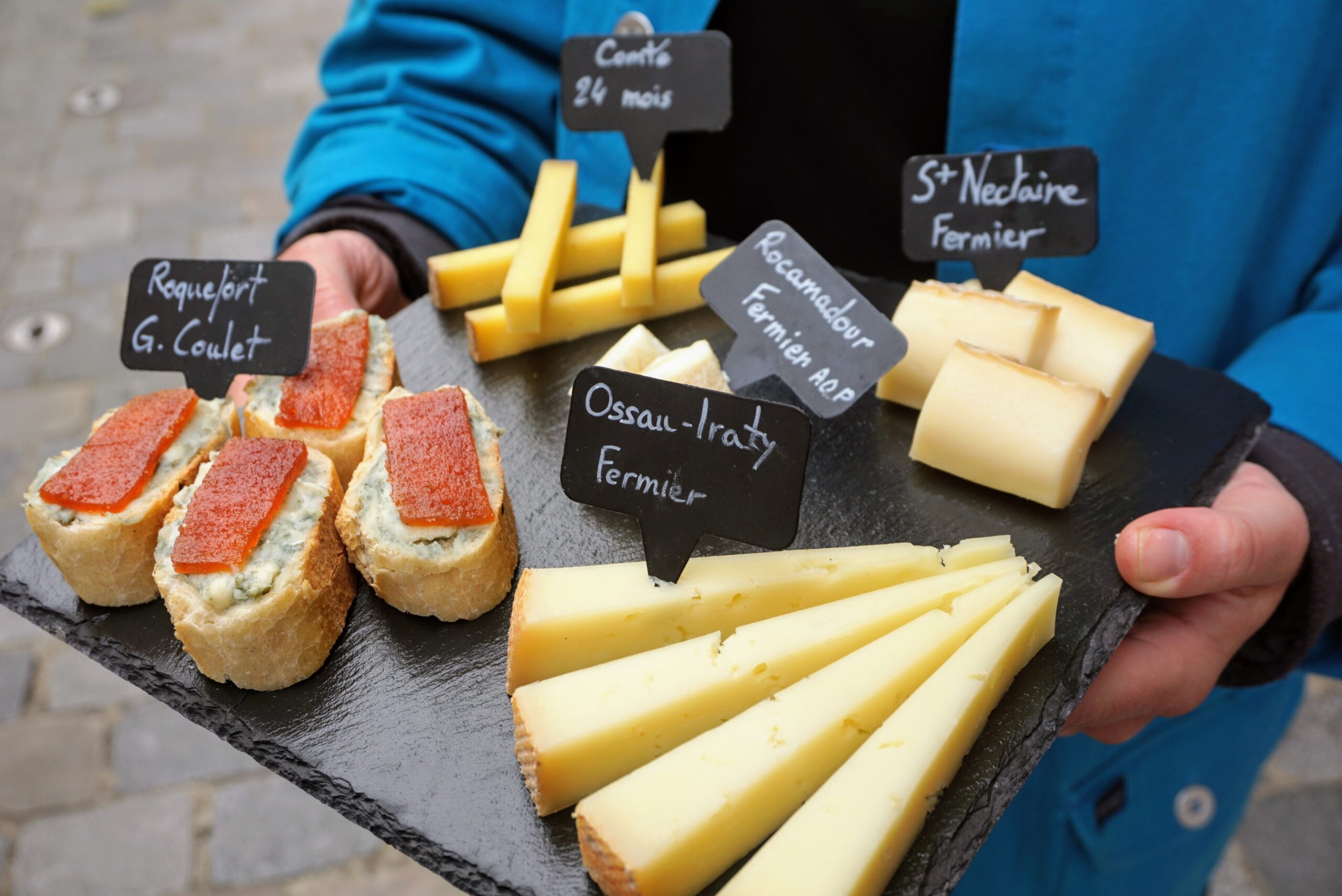 person holding a platter of labeled cheese.