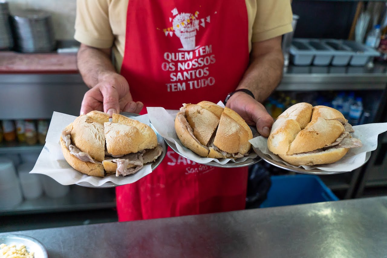 Employee holding 3 bifana sandwiches at O trevo restaurant in Lisbon