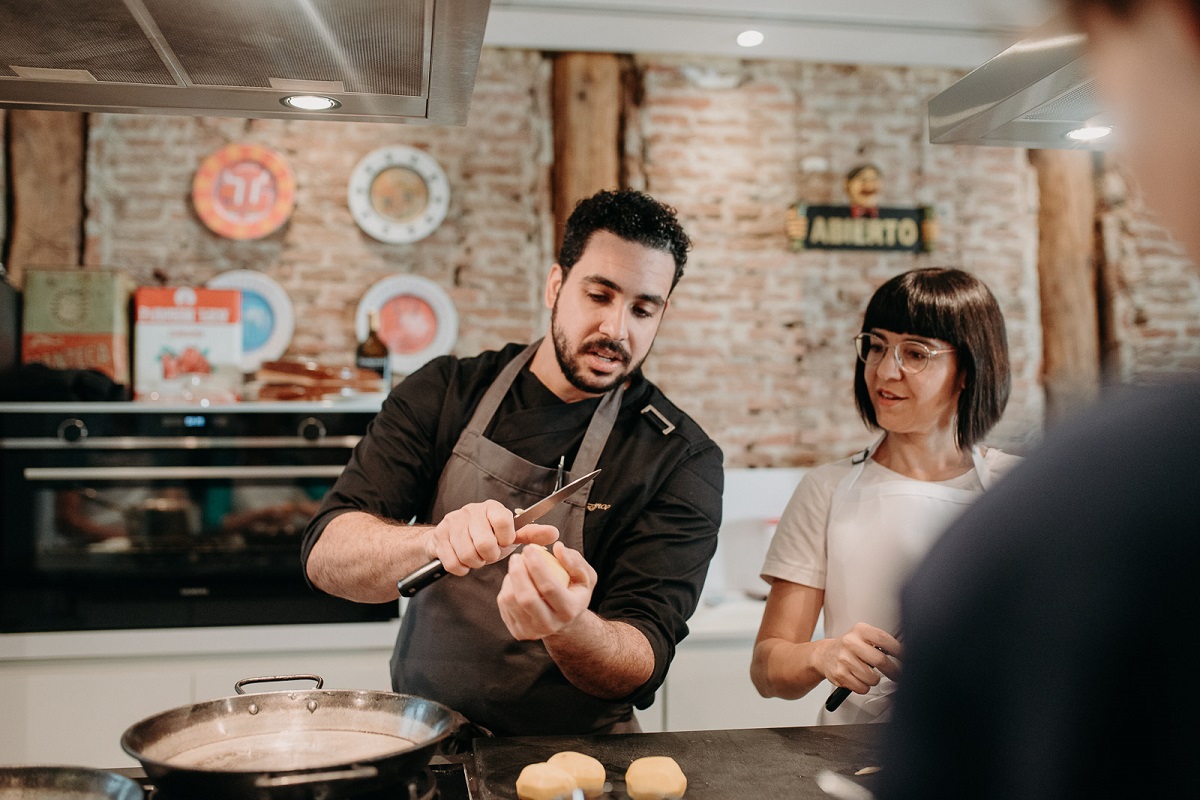 Student in cooking class looks as chef demonstrates how to do something in the kitchen