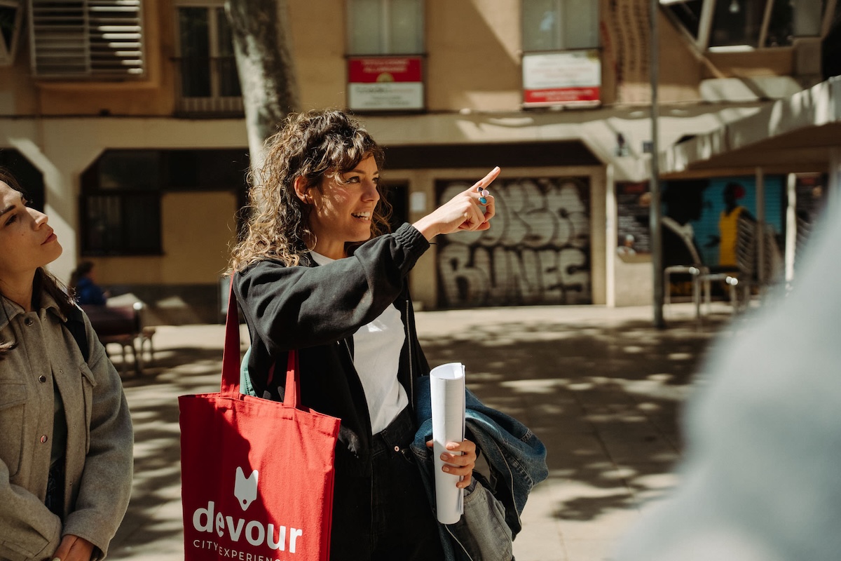 woman with red bag pointing out something to woman on her right
