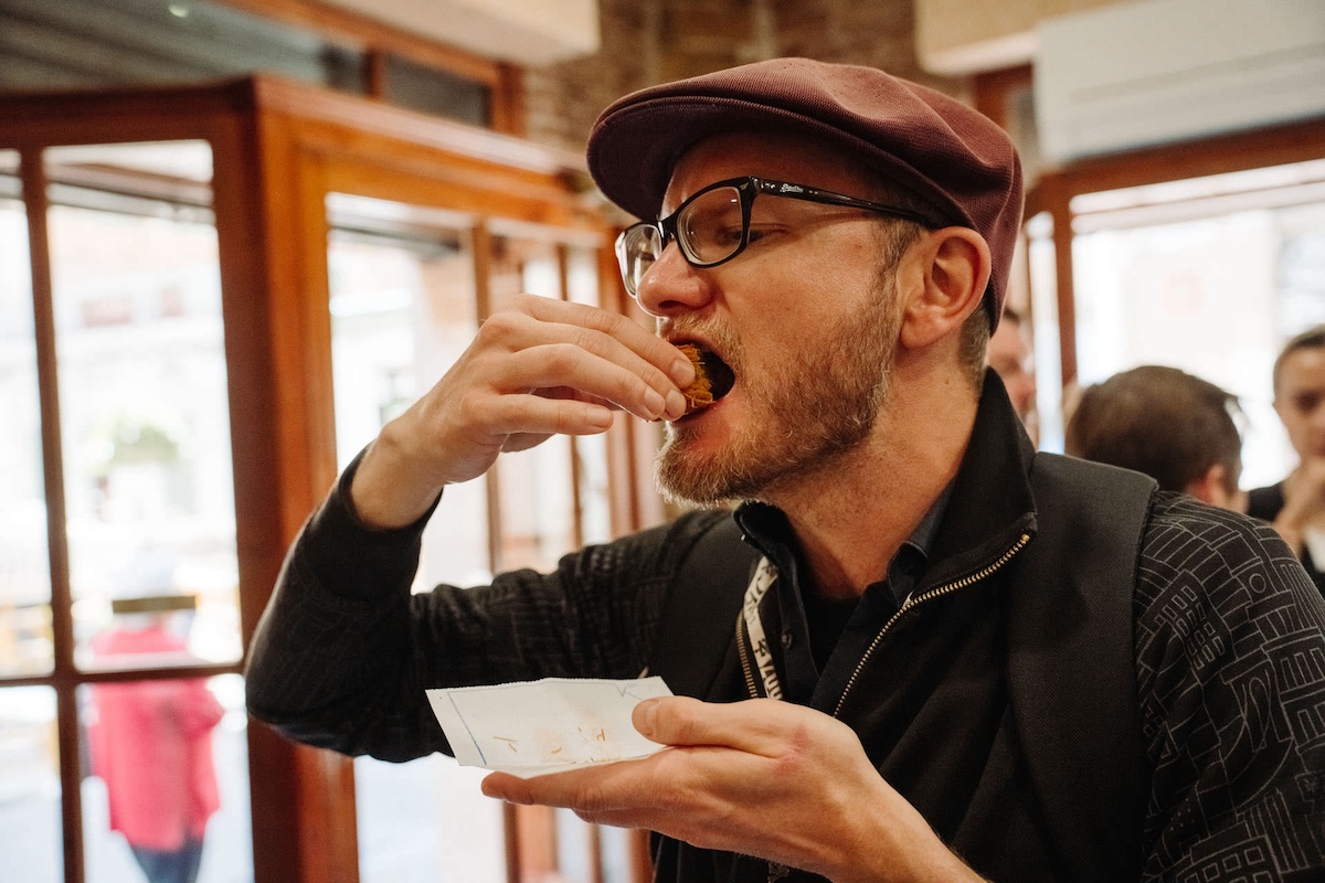 man in hat putting food in his mouth