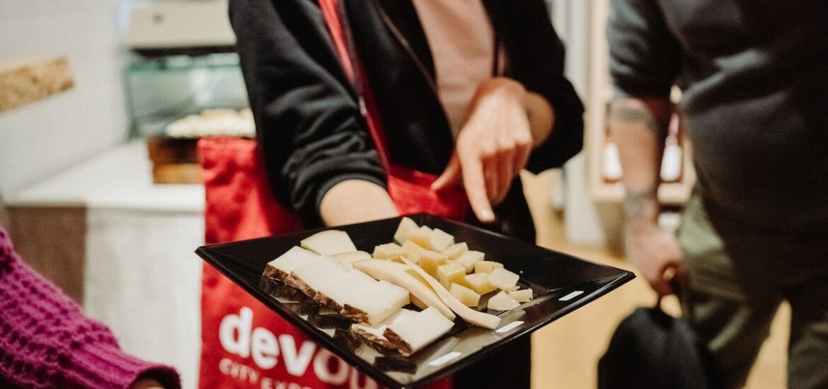 woman offering a plate with a selection of different cheeses on top