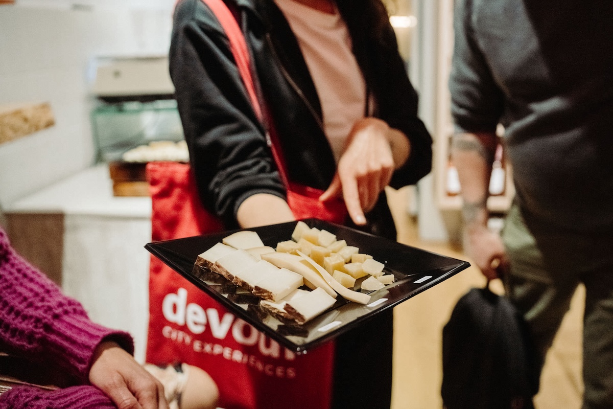 woman offering a plate with a selection of different cheeses on top