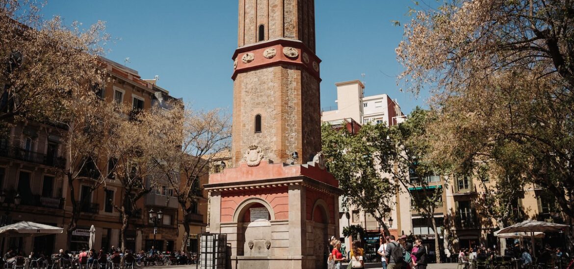 base of brick clock tower in city square in Barcelona in November.