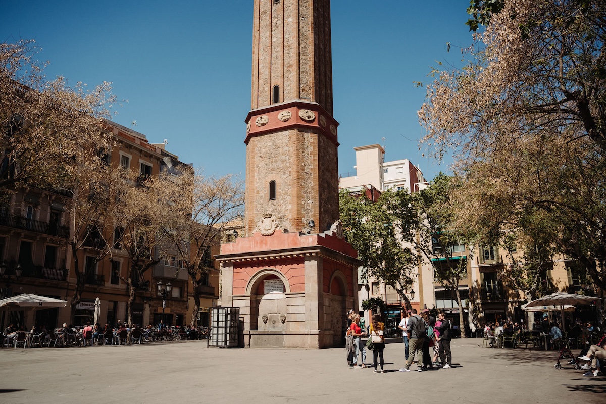 base of brick clock tower in city square in Barcelona in November.
