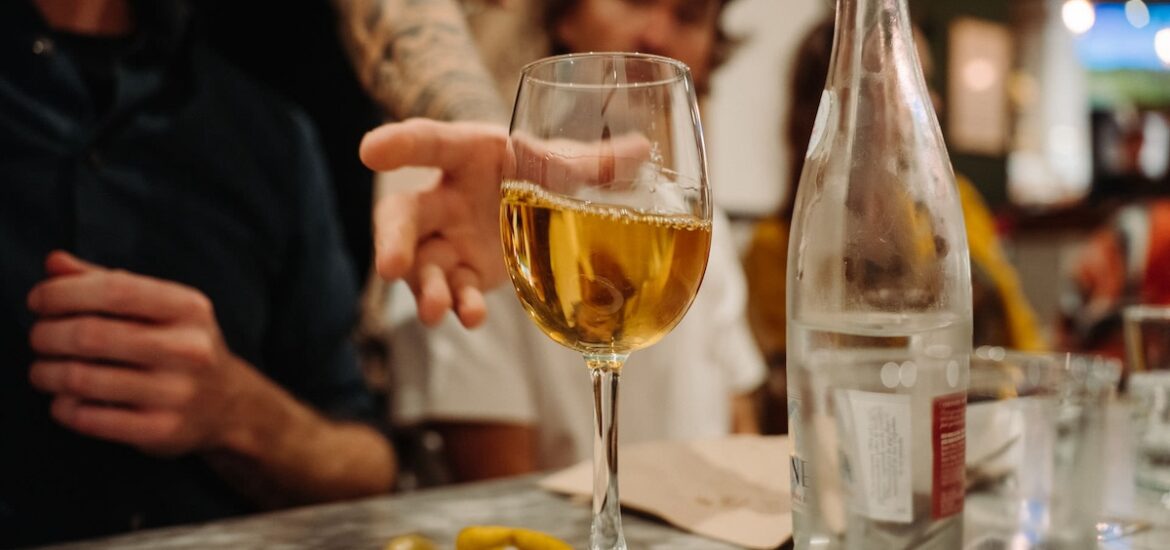 man reaching for a glass of white wine