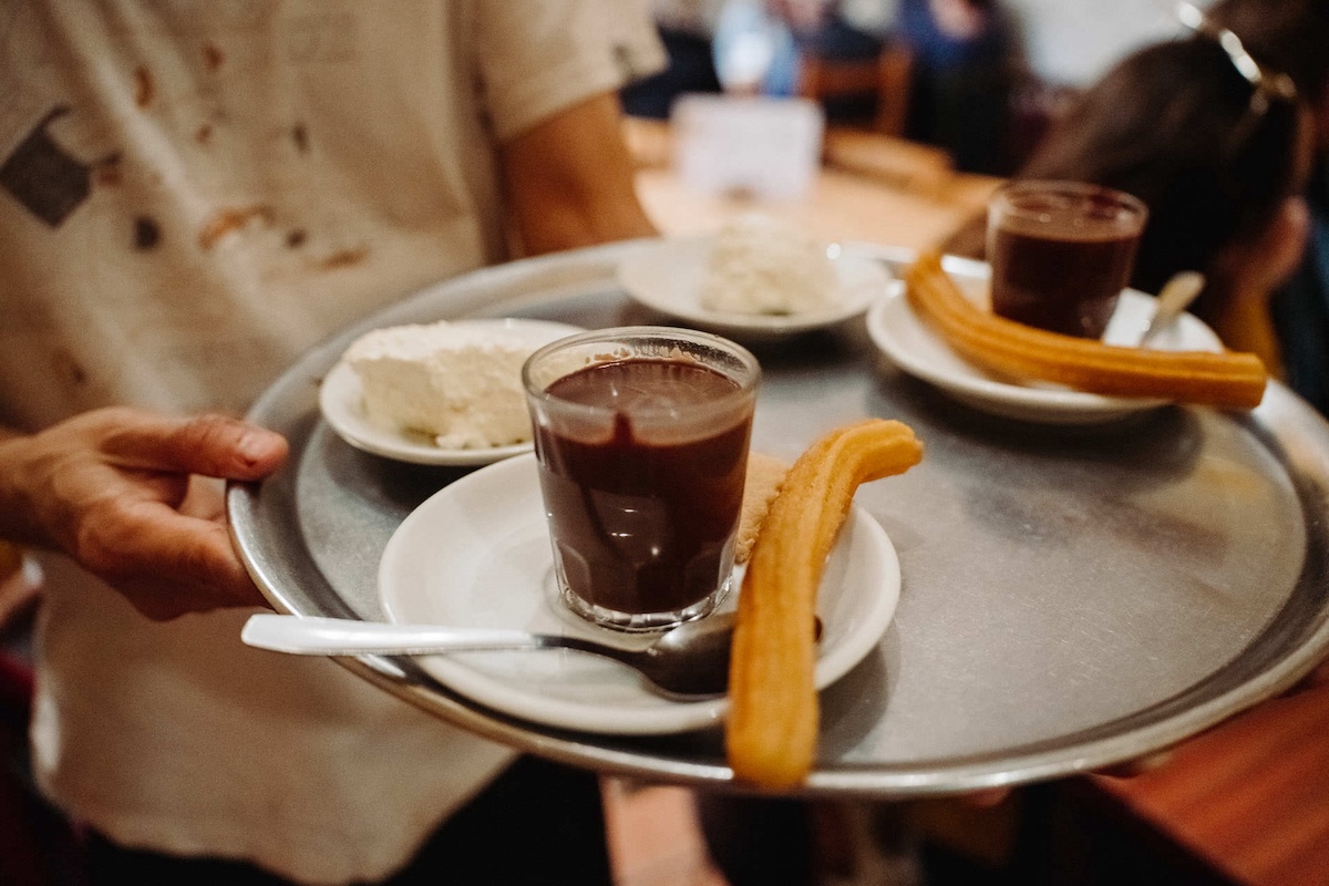 silver tray of glasses of hot chocolate and churros