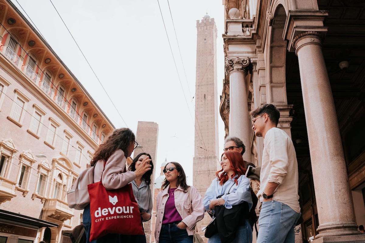 group of people on the street listening to tour guide with red bag