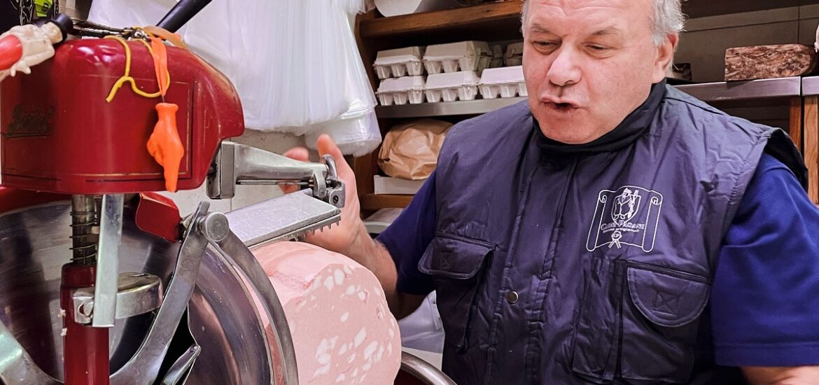 Food vendor slicing mortadella in Bologna, Italy, on a food tour