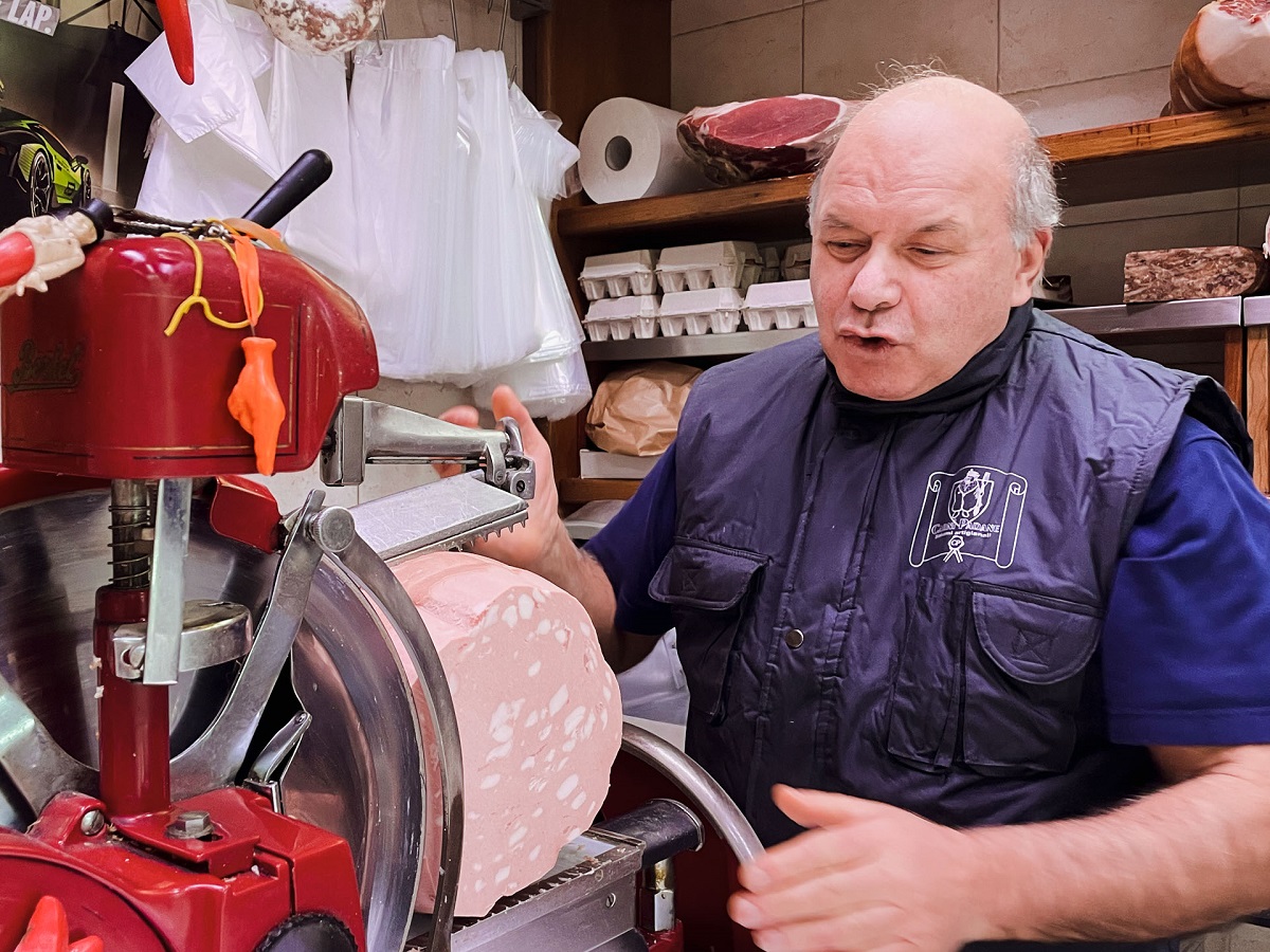 Food vendor slicing mortadella in Bologna, Italy, on a food tour