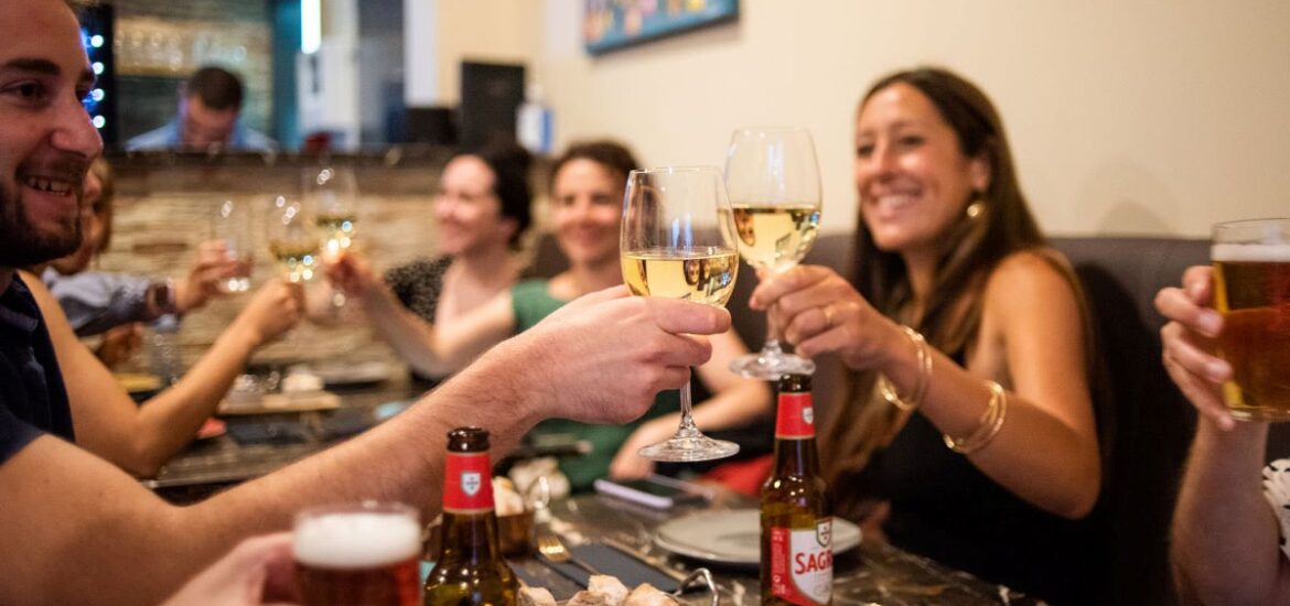 People at a restaurant in Portugal cheering wine glasses and drinking Portuguese beers.