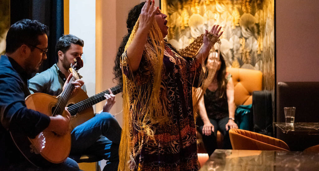 Fado show with singer, guitarists, and viewers at a restaurant in Lisbon, Portugal