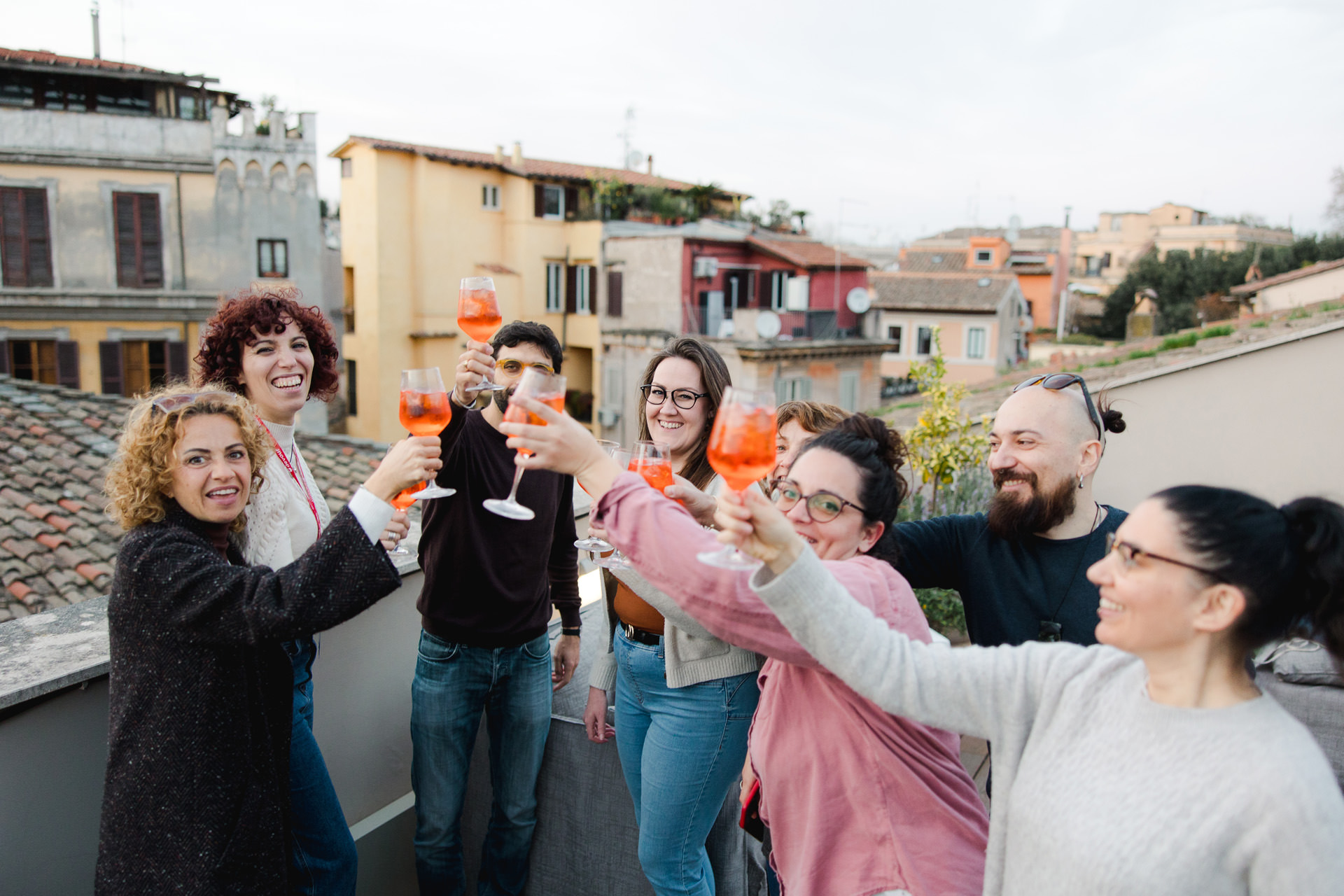 people toasting on a rooftop with wine glasses.