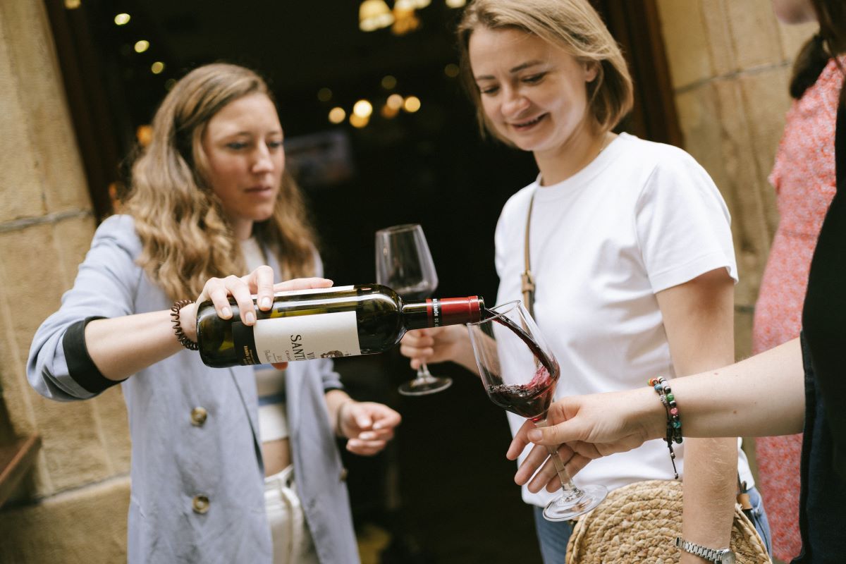 A guide pours a glass of red wine for a guest while on a food tour in San Sebastian