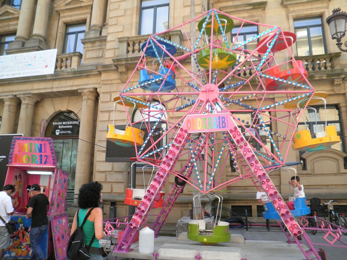 A child riding a pink mini Ferris wheel in San Sebastian. 