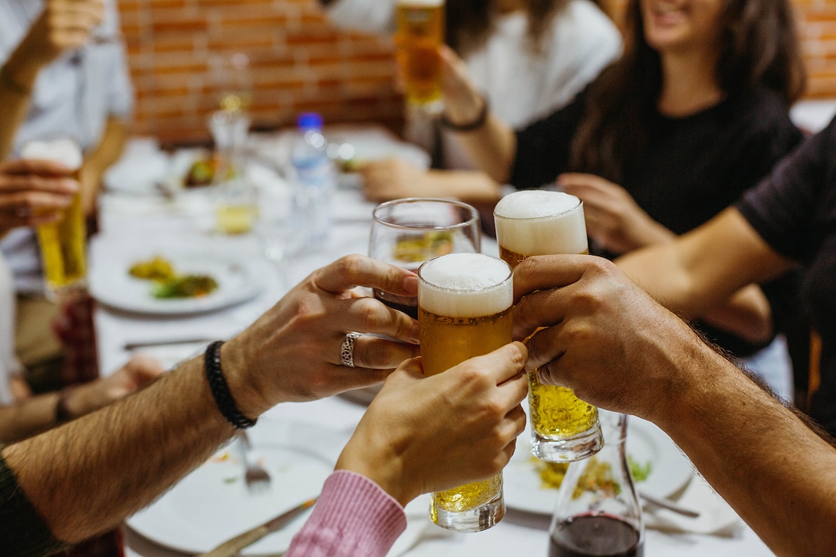 a group of people around a table toasting with draft beer