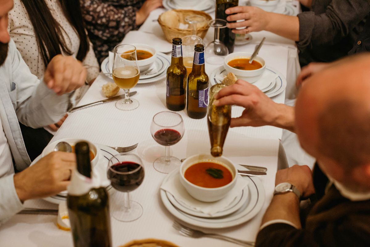 People eating Portuguese soup and drinking wine at a restaurant.